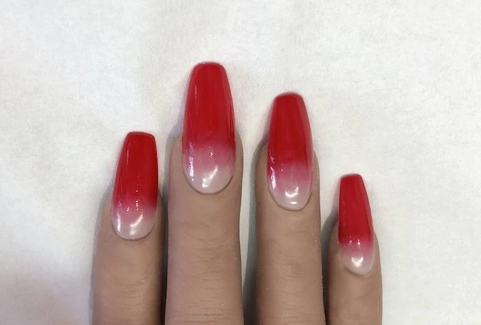 long square nails, nude to red gradient nail polish, ombre nail designs, hand placed on white background