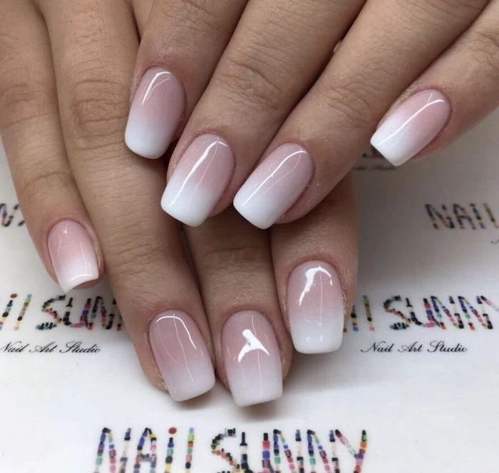 nude to white nail polish, red ombre nails, medium length squoval nails, hand placed on white surface