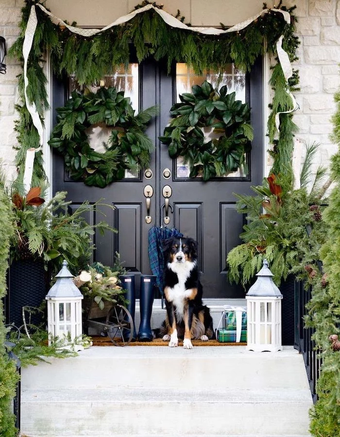 large outdoor christmas decorations, wreaths hanging on the door and door frame, dog standing on the stairs
