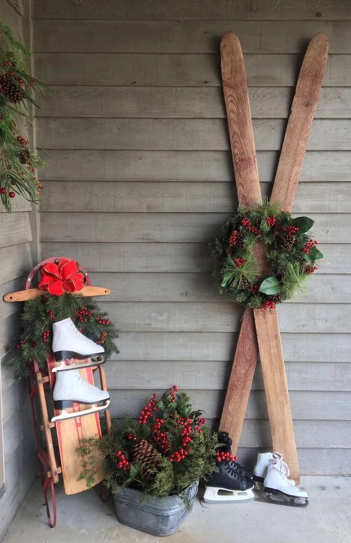 wooden skis decorated with wreath, wooden sled with ice skating shoes, grinch outdoor christmas decorations, arranged on front porch