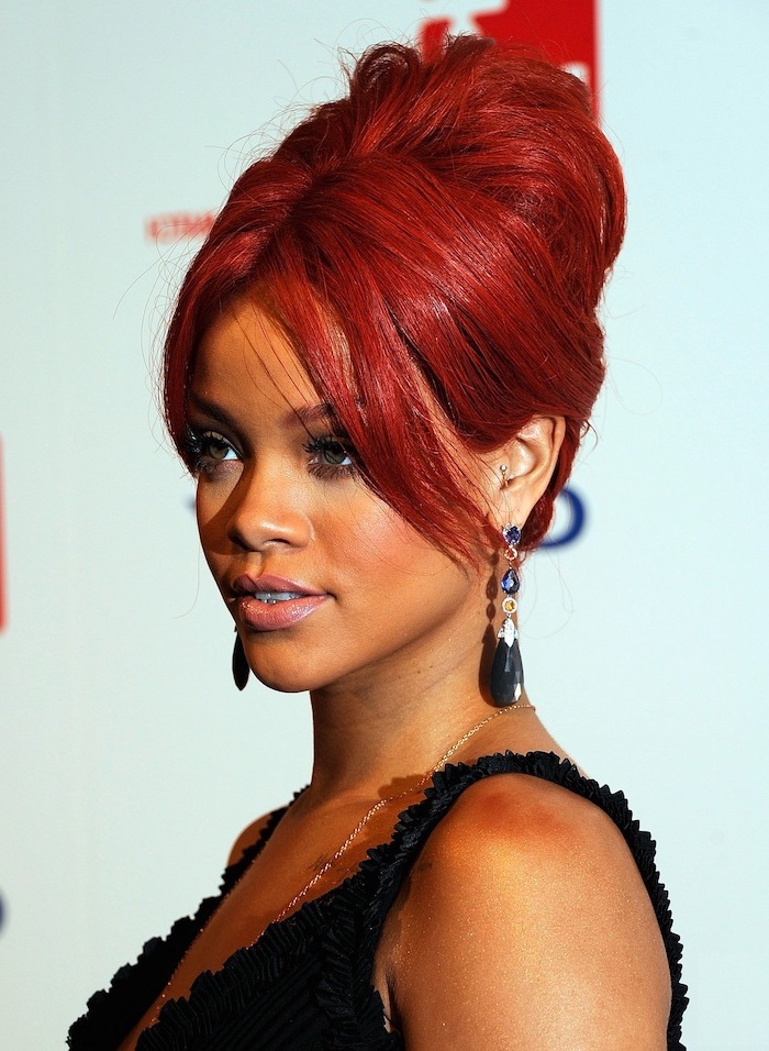 rihanna with red hair in a high updo, curly hair color ideas, wearing black dress, side swept bangs