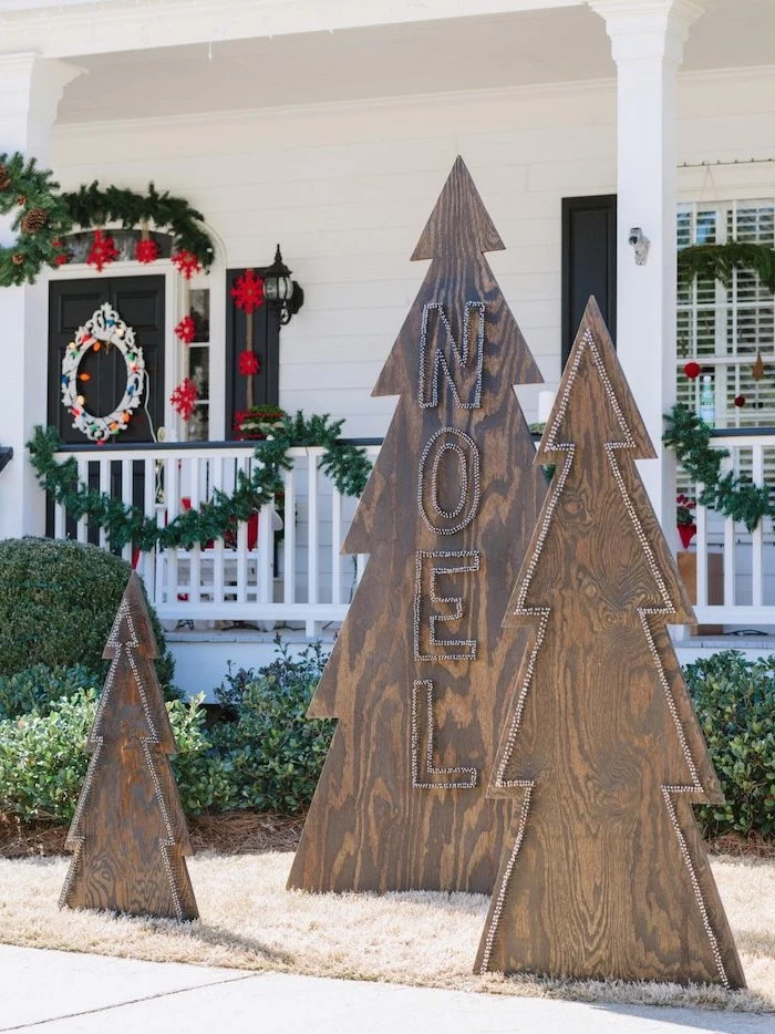 outdoor snowman decoration, three wooden boards in the shape of christmas trees, placed in front of the house