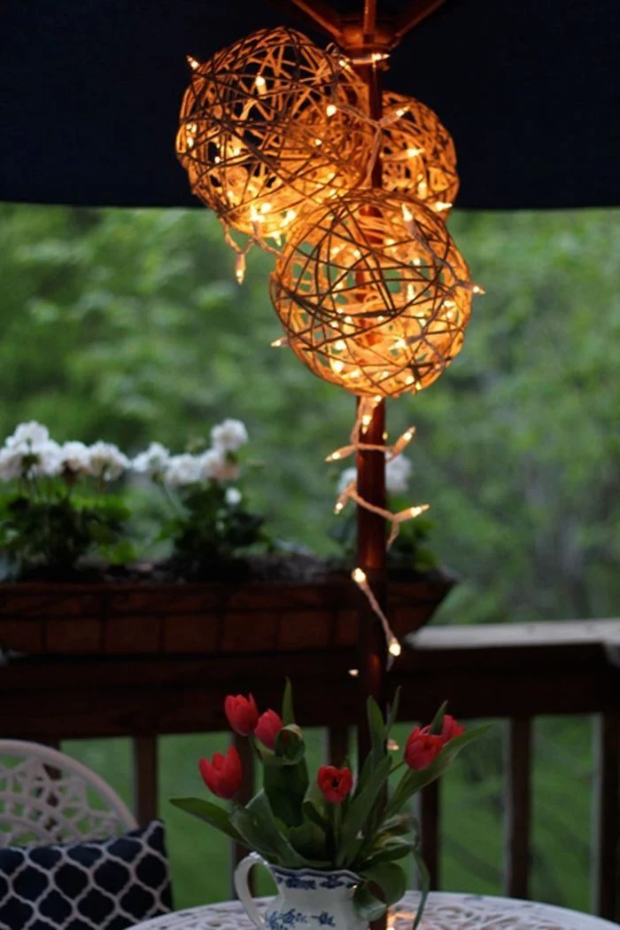 outdoor christmas decorations ideas, step by step diy tutorial, lanterns made of twine, hanging over a table, under an umbrella