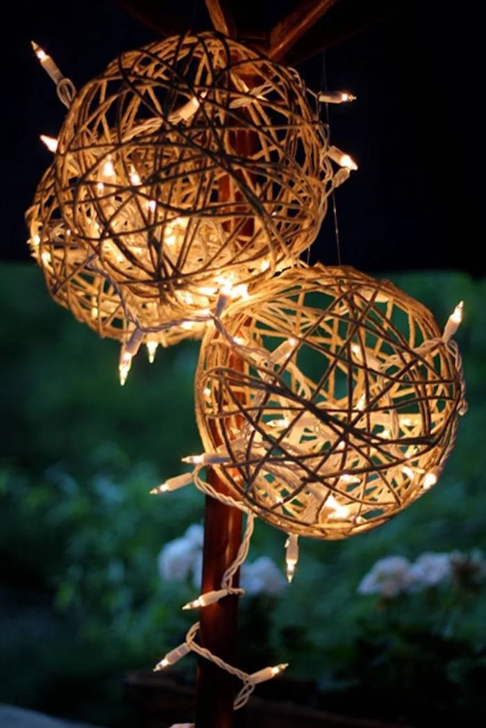 three lanterns made of twine, lights intertwined in them, outdoor christmas decorations ideas, hanging under an umbrella