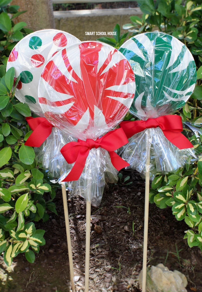 outdoor lighted christmas decorations, paper plate lollipops, decorations for your yard, wrapped with red ribbon