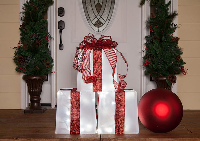 yard decorations, presents made of plastic containers, lights inside, wrapped with red ribbons, placed on wooden porch