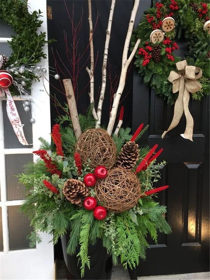 tree branches decorated with twine, pine cones and berries, outdoor snowman decoration, paced in front of a black door with wreath