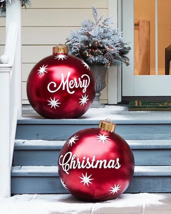 two large red baubles, merry christmas written on them, outdoor snowman decoration, placed on wooden staircase