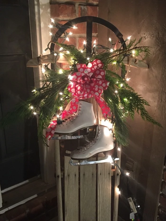 ice skating shoes on a sled, with tree branches and lights, placed on the porch, outside christmas decoration ideas