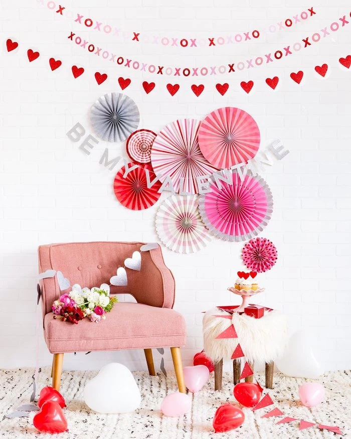 be my valentine banner, hearts garland hanging on white wall, pink armchair, valentines day decor, heart shaped balloons on the floor