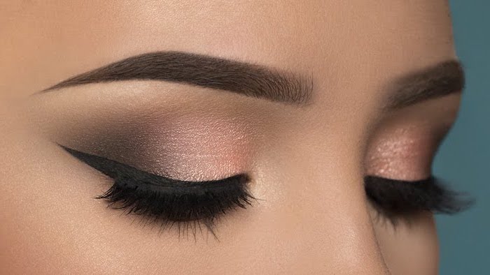 rose gold smokey eye, black cat eyeliner, blue eyeshadow, woman with dark thick eyebrows