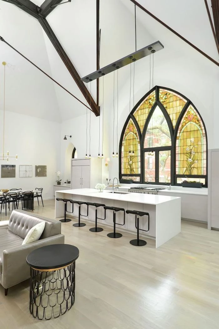 kitchen with white kitchen island and black stools, stained glass windows, cathedral ceiling and window, wooden floor