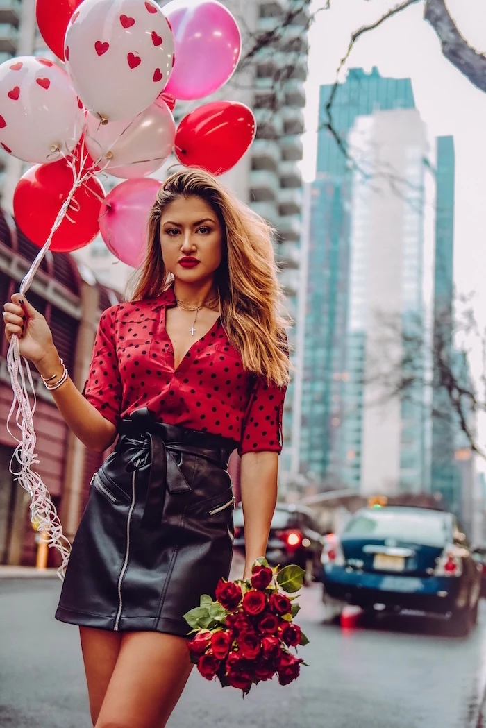 woman holding a bunch of balloons, valentines day outfits, wearing black leather skirt, red blouse with black polka dots