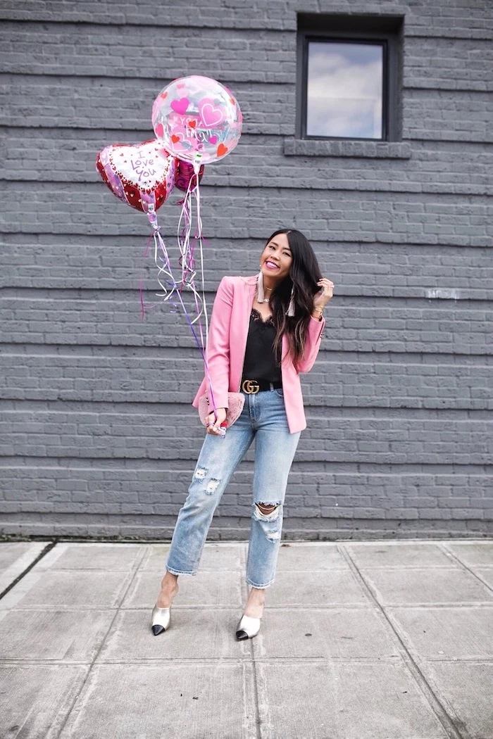 woman holding a bunch of balloons, valentines day dresses, wearing black top and jeans, pink blazer 