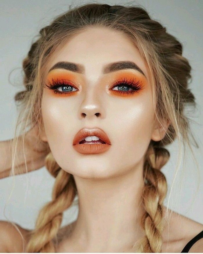 blonde woman with two braids, blue eyeshadow, orange eyeshadow color, dark brown matte lipstick