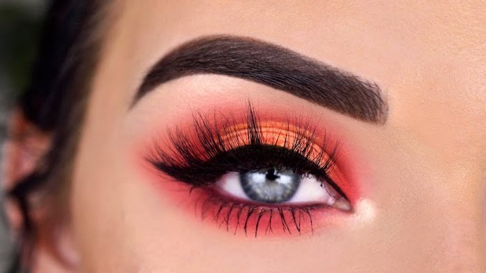 woman with blue eyes, dark thick eyebrows, orange and red eyeshadow colors, black cat eyeliner, eyeshadow tutorial