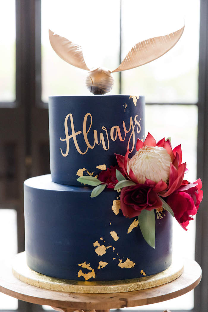 two tier cake, covered with blue fondant, golden snitch topper, happee birthdae harry, large flower on the side