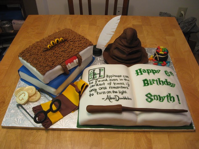 cakes in the shape of different books, arranged on silver tray, happy birthday harry cake, gryffindor scarf and sorting hat