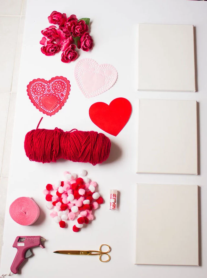 step by step diy tutorial, valentine decorations, white canvases, pom poms and yarn, faux flowers and hearts for decoration