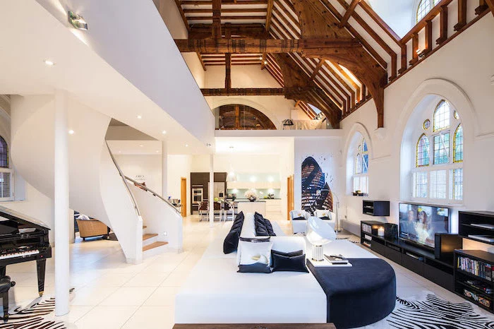 large two storey house with cathedral ceiling, stained glass panels, black and white sofa, large staircase and white tiled floor
