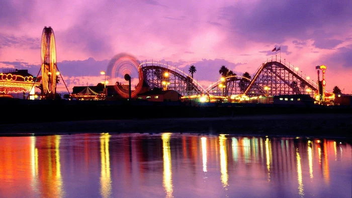 amusement park on a pier, photographed at sunset, aesthetic desktop wallpaper, lights illuminated in the ocean