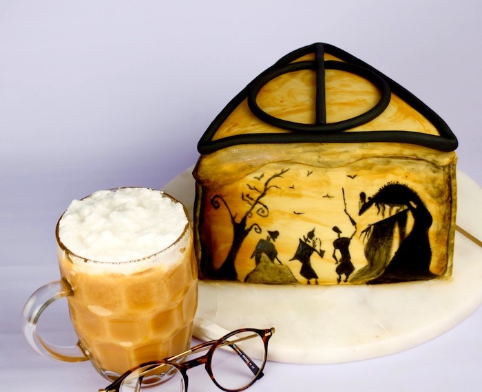 triangle one tier cake, story of brothers and deathly hallows illustrated on it, harry potter cake hagrid, butterbeer on the side