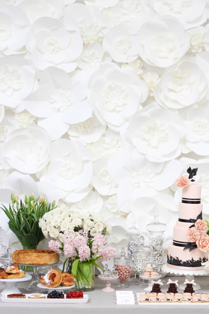 white paper flowers in different shapes and sizes, how to make tissue paper flowers, arranged for a backdrop behind a desserts table