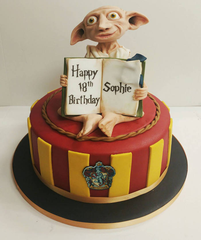 one tier gryffindor cake with red and yellow fondant, harry potter cake hagrid, dobby made of fondant on top