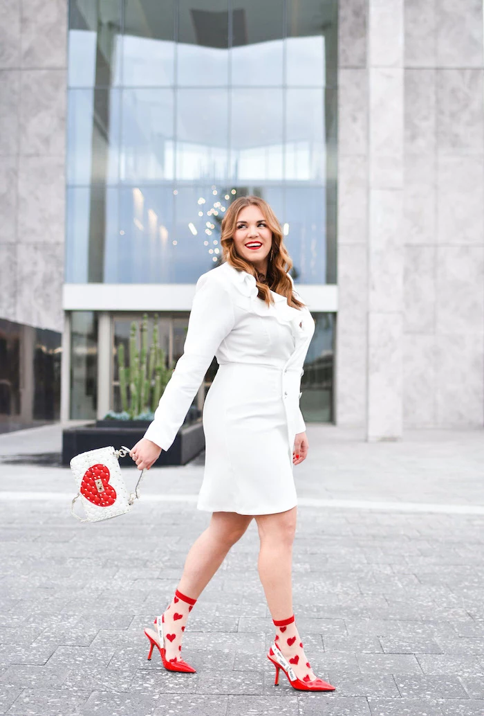 woman smiling, walking on sidewalk, red dress for valentine's day, wearing white dress with long sleeves, red heels with socks with hearts