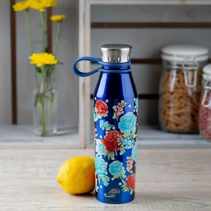 blue stainless steel water bottle, floral motifs drawn on it, romantic gifts for her, placed on wooden surface, lemon next to it