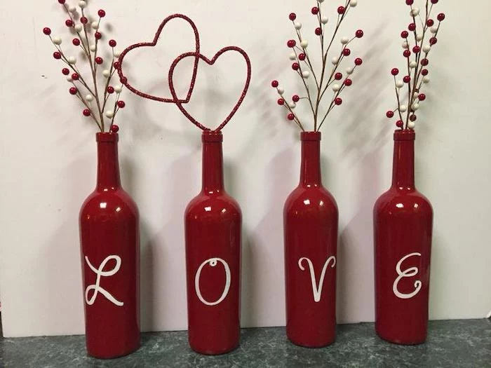 wine bottles painted in red, love spelled on them, filled with faux twigs in red and white, valentine's day decoration ideas