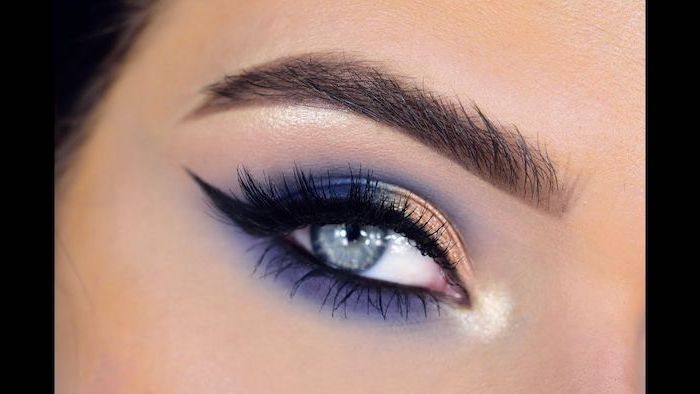 golden and purple blue eyeshadow colors, black cat eyeliner, green eyeshadow, woman with blue eyes and dark eyebrows