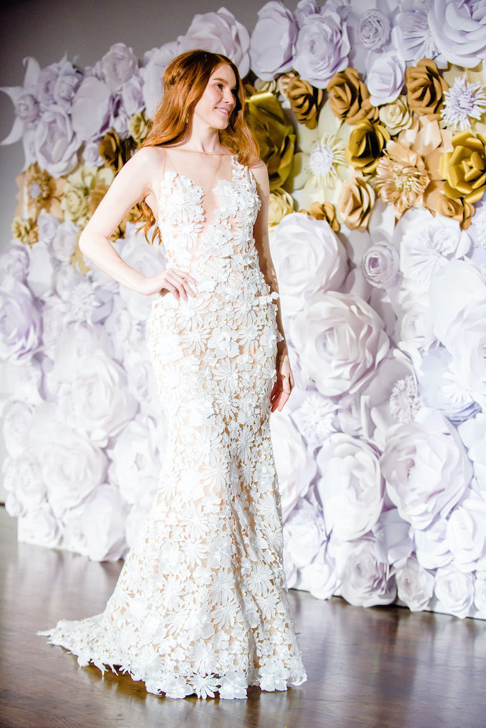 woman with long red hair, wearing a white lace wedding dress, giant paper flowers, large backdrop with white and gold paper flowers