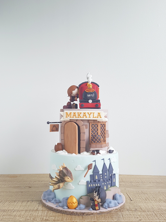 harry potter themed cake, two tier cake, portraying hogwarts and hut, hogwarts express and hermione on top