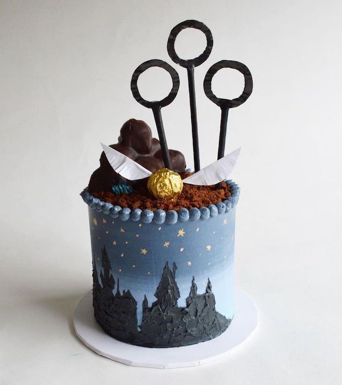 one tier cake with blue fondant, harry potter themed cake, qudditch hoops and golden snitch toppers, hogwarts drawn on it