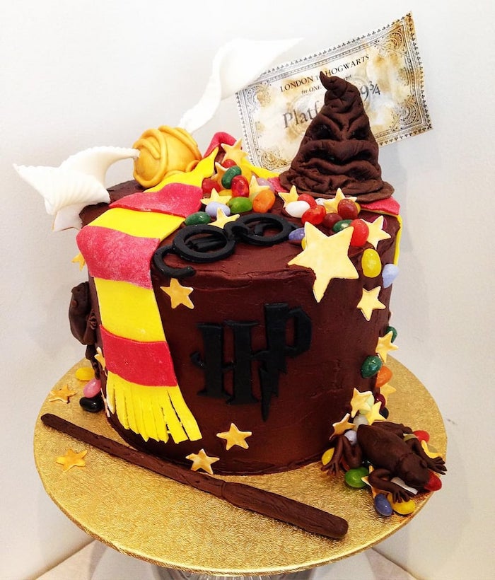 cake with brown buttercream, sorting hat and glasses, golden snitch and gryffindor scarf, made of fondant on top, harry potter themed cake