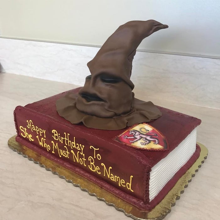 one tier cake in the shape of a book, harry potter themed cake, she who must not be named, sorting hat on top