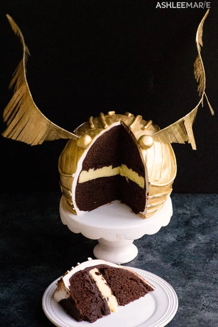 slice cut out of golden snitch cake, placed on white plate, harry potter birthday cake, black background