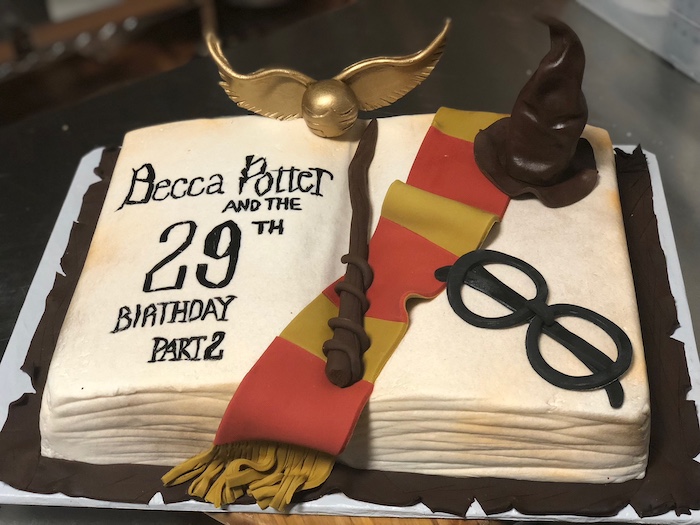 cake in the shape of open book, harry potters birthday cake, gryffindor scarf wand and glasses, made of fondant on top