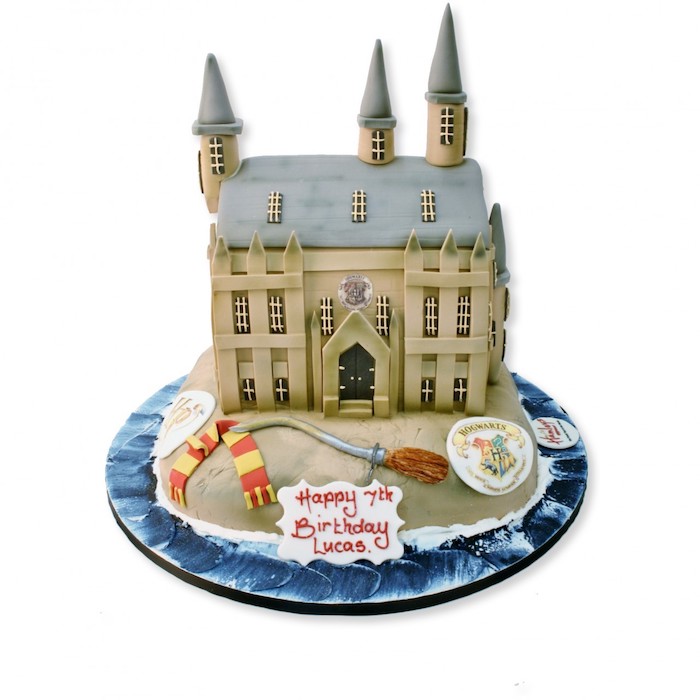 hogwarts cake made with fondant, harry potters birthday cake, broom and gryffindor scarf on the side, white background