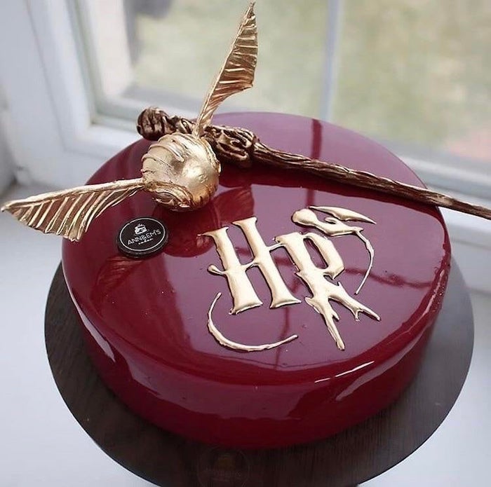 harry potter sheet cake, round one tier cake, covered with red glaze, golden snitch and wand on top, placed on wooden tray