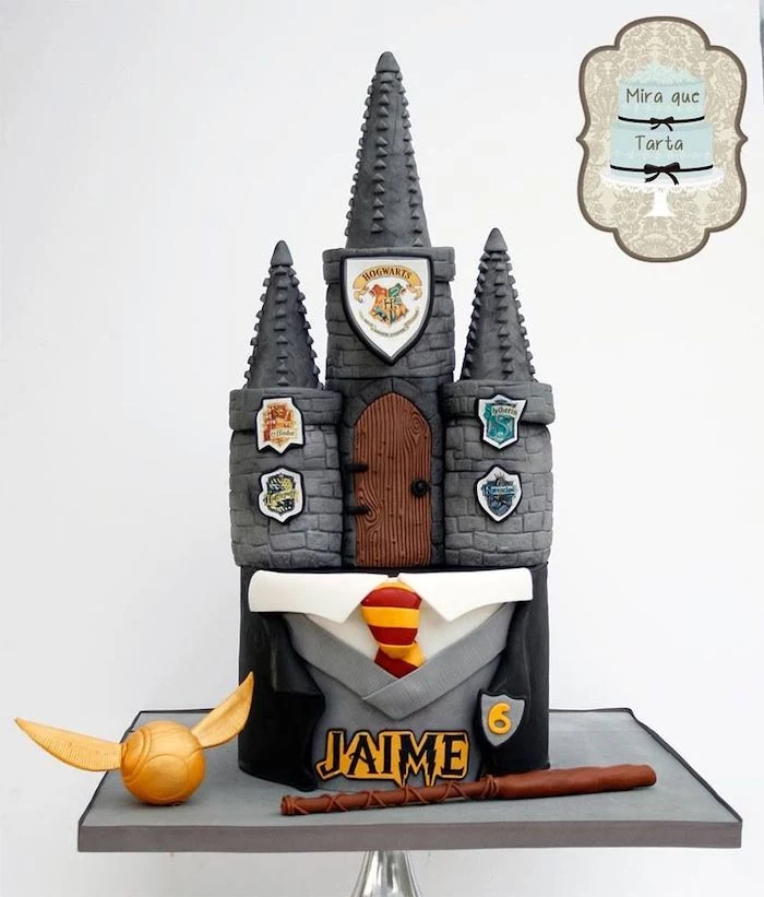 two tier hogwarts cake, harry potters birthday cake, gryffindor uniform, golden snitch and wand on the side
