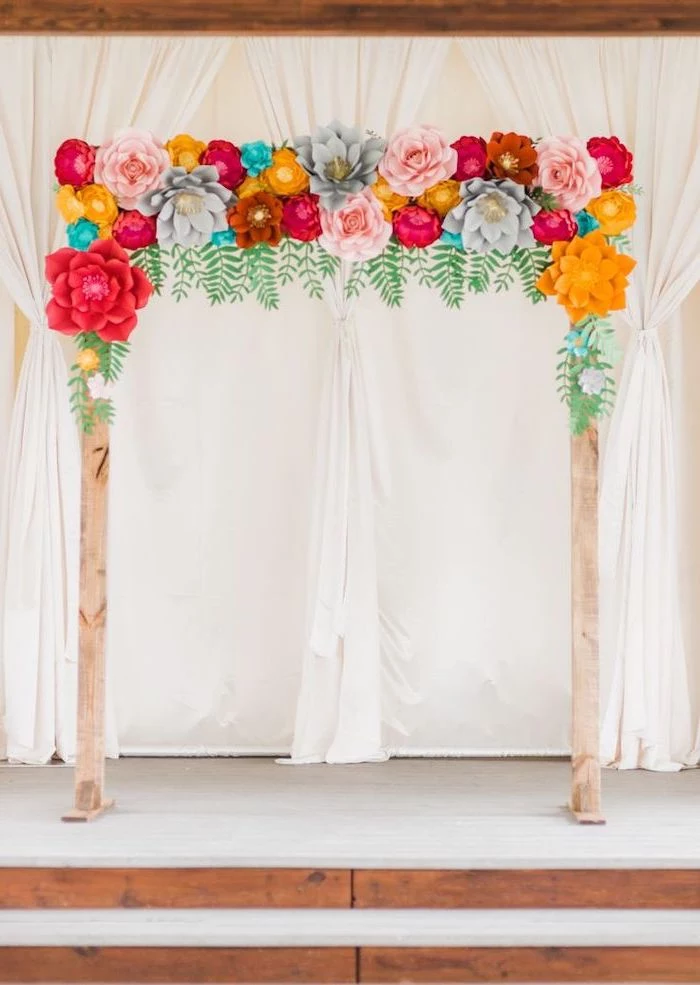 wooden arch, decorated with colorful paper flowers, paper flower decorations, white curtains in the background
