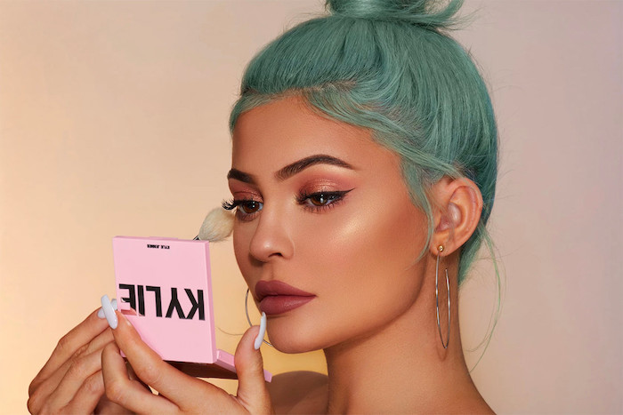kylie jenner, holding kylie cosmetics powder, how to apply eyeshadow, putting on powder, turquoise hair in a bun