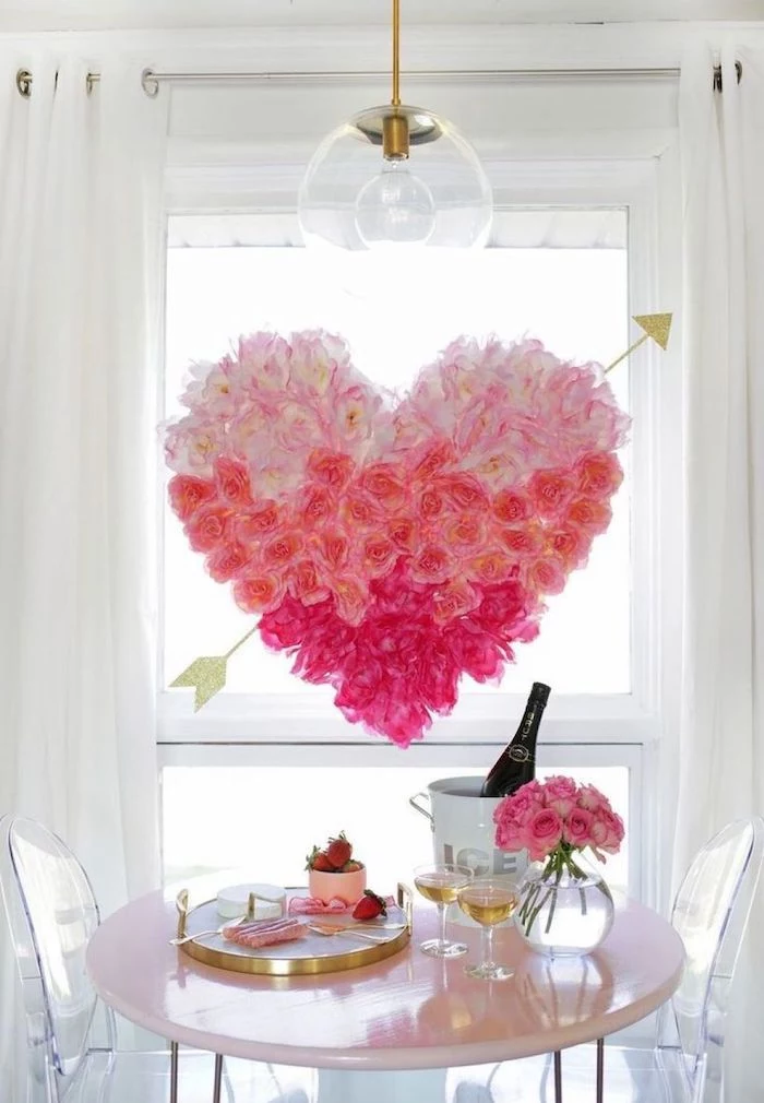 large heart made of pink flowers, hanging over table, set for two with champagne and strawberries, diy valentine decorations