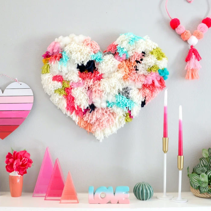 large heart made of pom poms, diy valentine decorations, pink wooden heart, hanging on grey wall, decorations on white surface