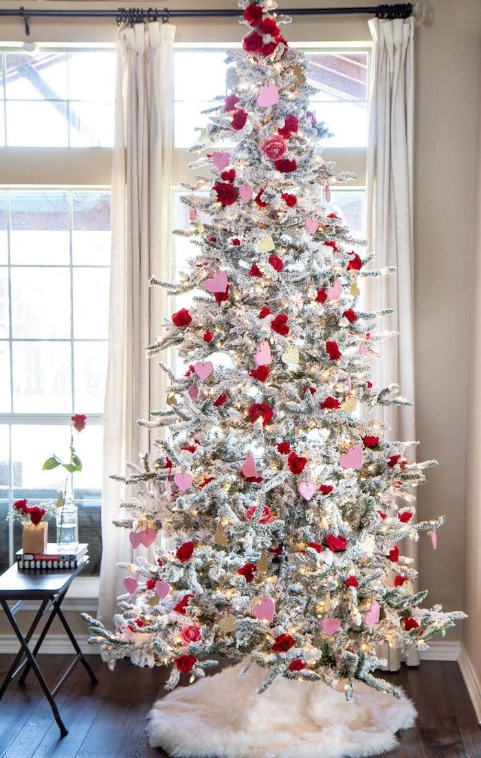 tree with faux snow, decorated with red and pink hearts, outdoor valentine decorations, placed on wooden floor