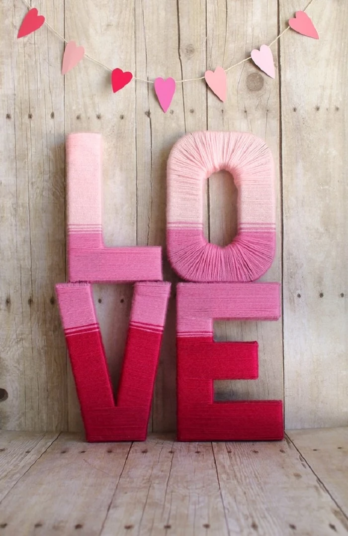 outdoor valentine decorations, hearts garland, hanging on wooden wall, love sign wrapped with pink yarn, placed on wooden surface