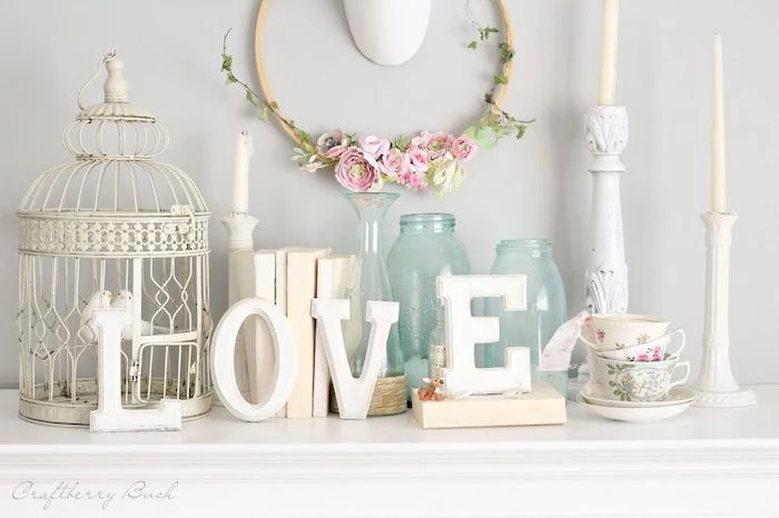 love wooden sign, wreath made with pink flowers, vintage candlesticks and vases, outdoor valentine decorations, arranged on mantel
