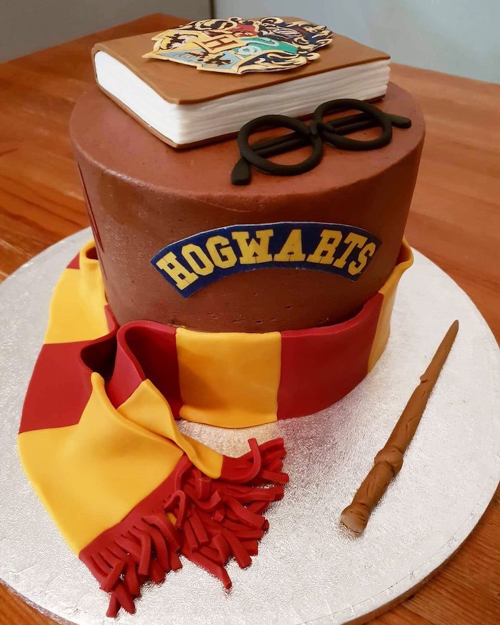 one tier hogwarts cake, covered with brown buttercream, 11th birthday cake, gryffindor scarf made of red and yellow fondant around it